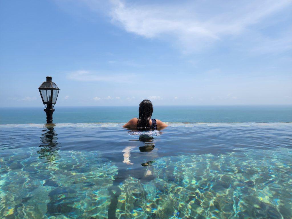 Woman at the edge of a rooftop pool in Colombo, Sri Lanka looking out at the ocean